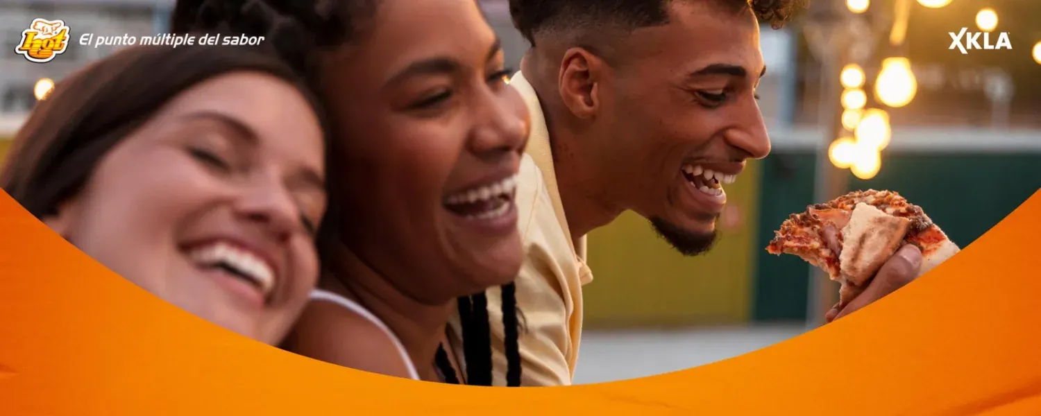 Tres amigos riendo mientras comen pizza, en la campaña de los 50 años de HOT